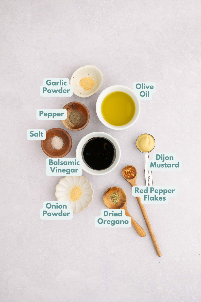Ingredients to make grilled vegetable pasta salad in bowls and measuring cups on a counter.