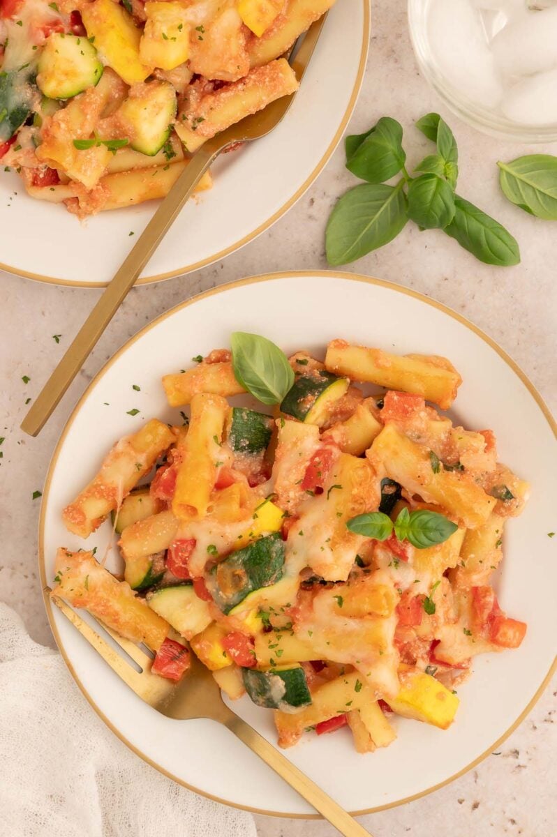 Vegetable Baked Ziti on two plates with gold forks sitting on it.