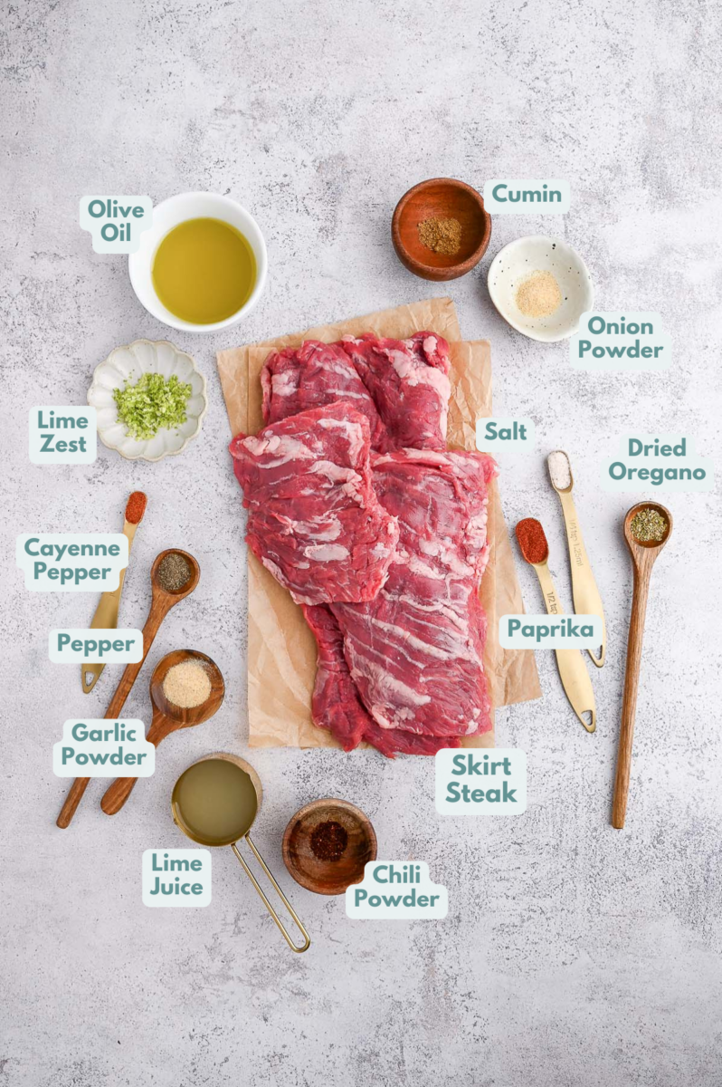 Labeled ingredients for chili lime steak in bowls and measuring cups sitting on a marble countertop