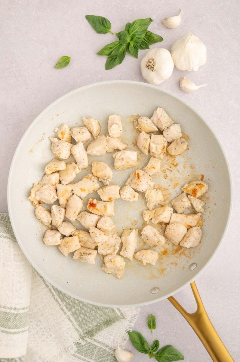 Cubed chicken pieces in a skillet after being browned.