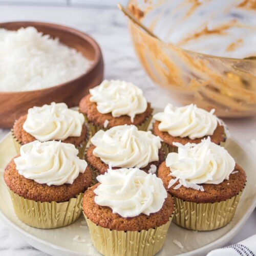 Platter of seven coconut sugar cupcakes topped with swirls of vanilla frosting.