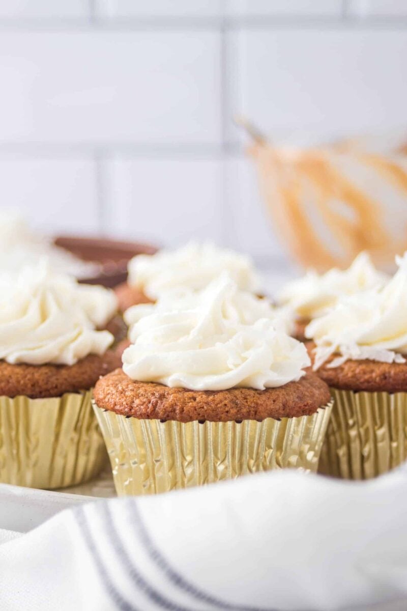Side view of frosted coconut cupcakes on a cake plate.