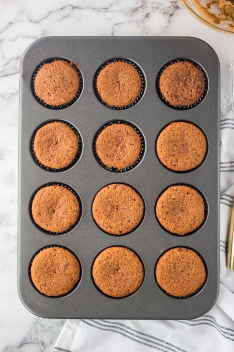 Overhead, looking down on 12 baked vanilla cupcakes in a muffin tin.