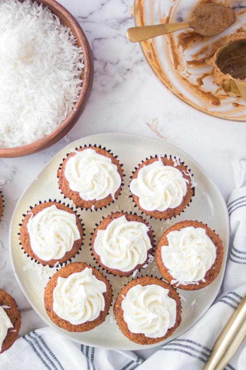 Overhead, looking down on seven frosted coconut sugar cupcakes on a small plate.