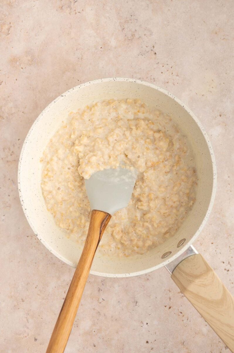 Oatmeal cooking on the stove with a spatula in it.