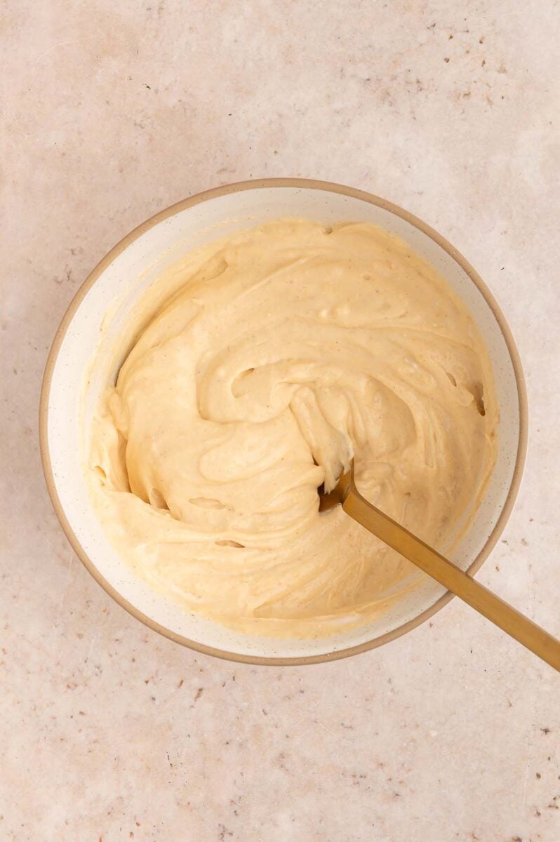 Greek Yogurt, peanut butter and vanilla protein powder being mixed together in a small bowl with a spoon in the mixture.