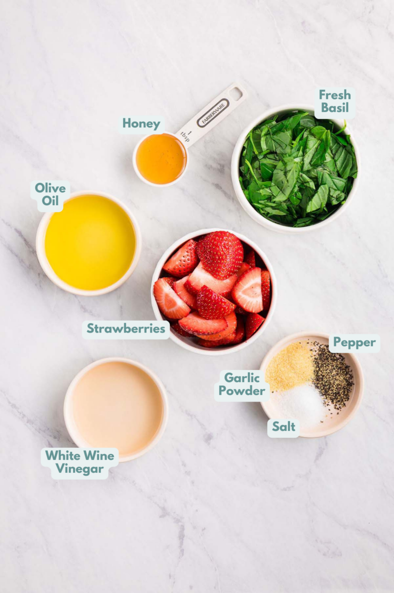 Labeled ingredients to make strawberry vinaigrette in small bowls and measuring cups.