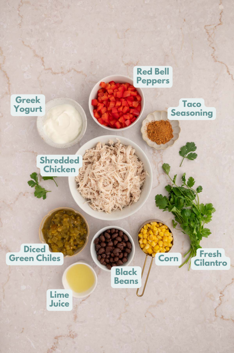 Ingredients to make taco chicken salad in bowls and measuring cups on a counter.