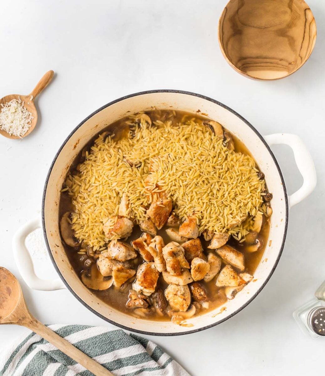 Ingredients for chicken marsala orzo in a dutch oven before fully mixing together and cooking.