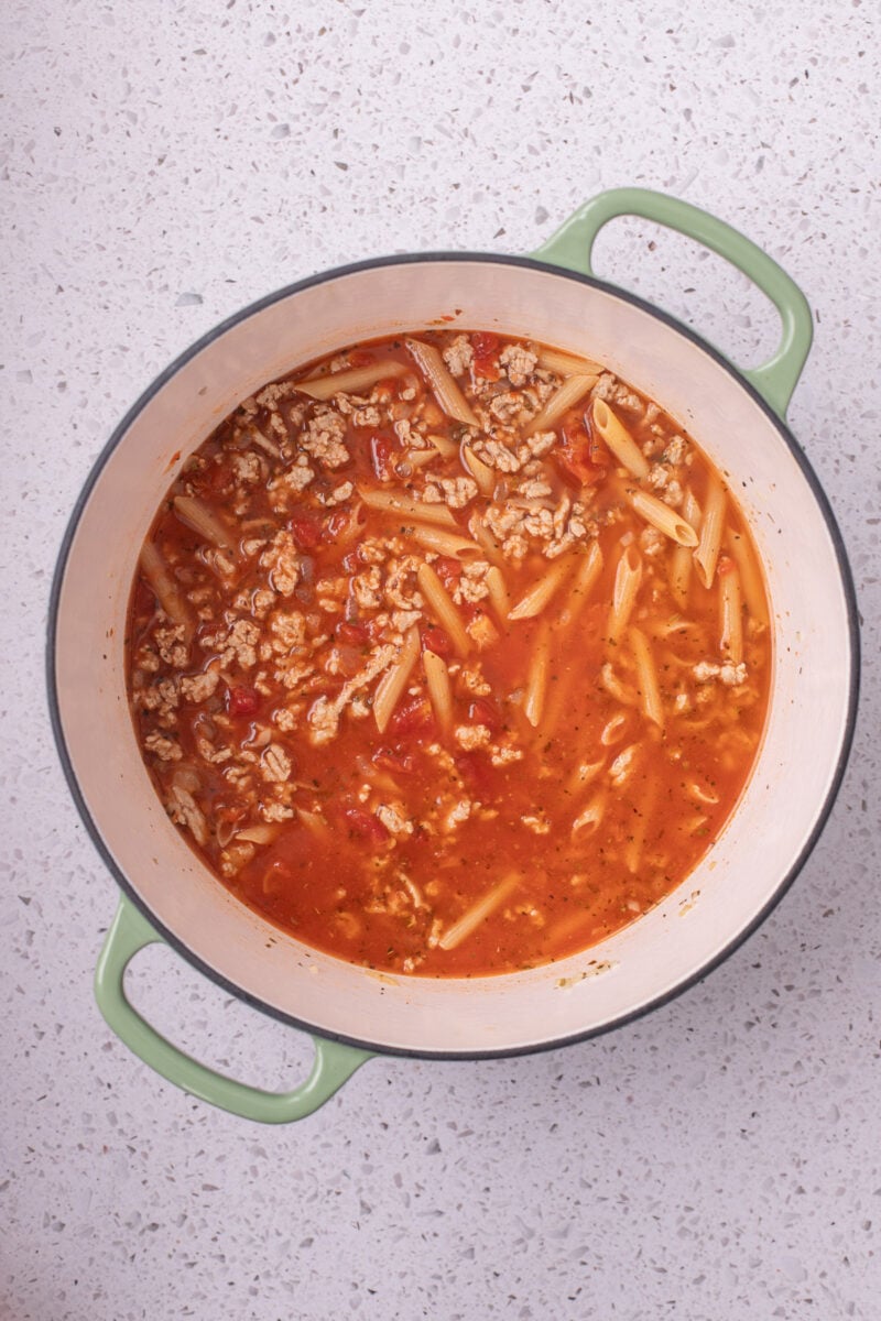 Ingredients for ground turkey pasta in a large pot mixed together, but not cooked yet.