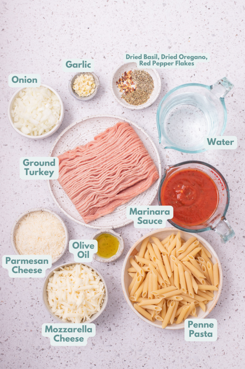 Labelled ingredients for cheesy turkey pasta laid out in separate bowls.