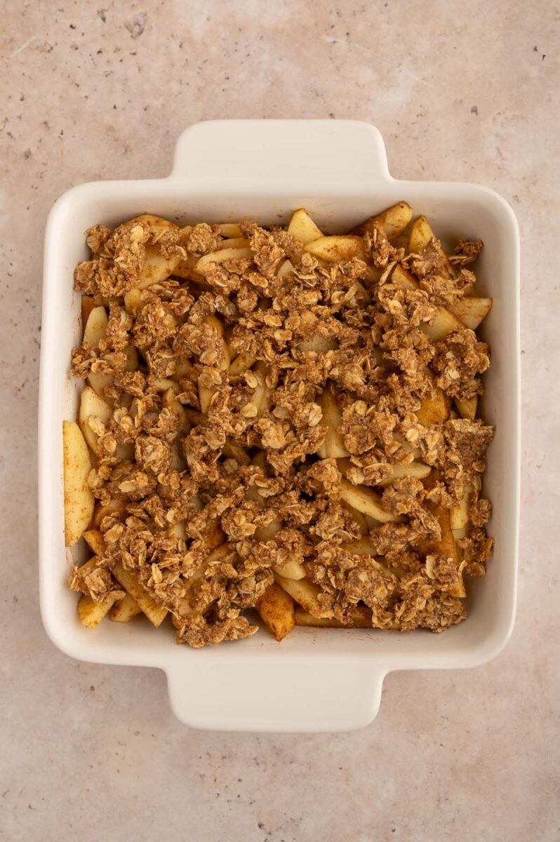 An overhead shot of a healthy apple crisp in a white square baking dish.
