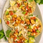 Four quick fish tacos on tortillas garnished with cabbage and lime slices.