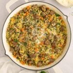 Italian wedding orzo in a skillet on a counter with fresh herbs and ingredients on the side.