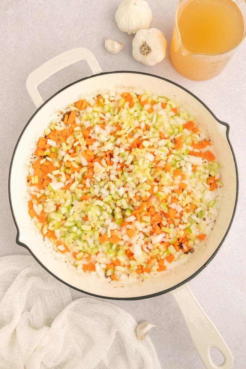 Carrots, celery, and onions in a skillet softening for italian wedding orzo.