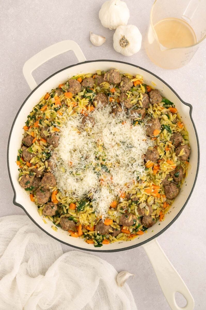 Italian wedding orzo topped with parmesan cheese in a large skillet.