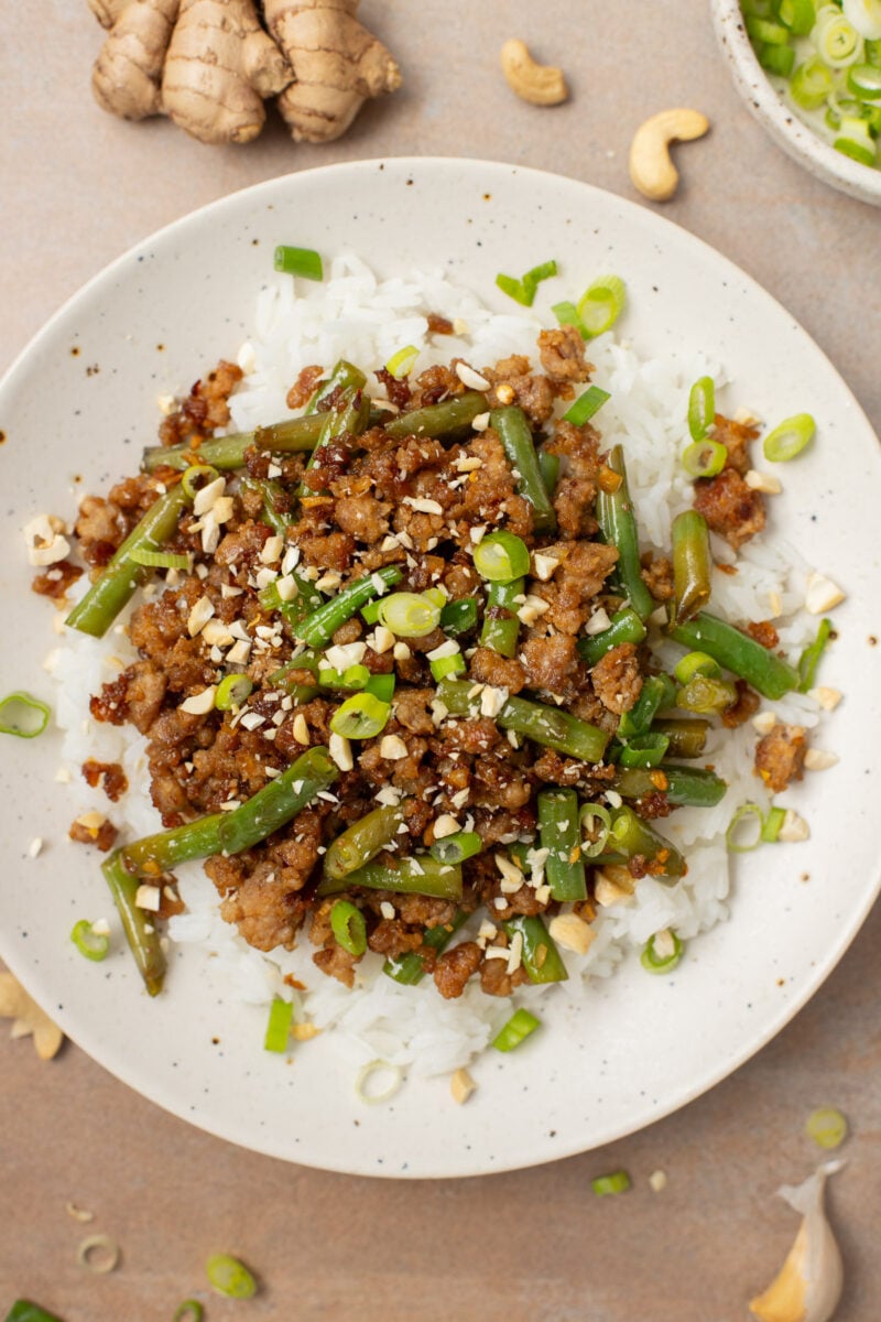 A plate of ground pork stir fry on a bed of white rice.