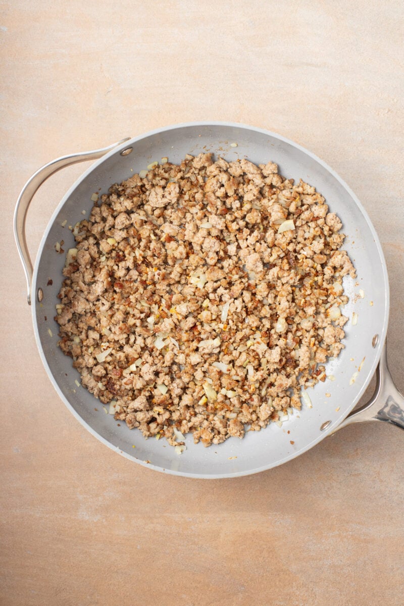 Onion and garlic in a pan with ground pork to make a stir fry.
