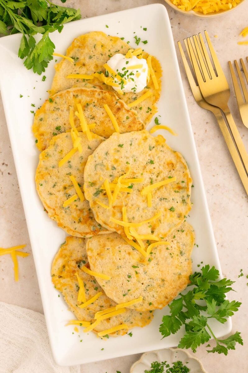 Savory Pancakes on a white platter with fresh parsley on the side. 