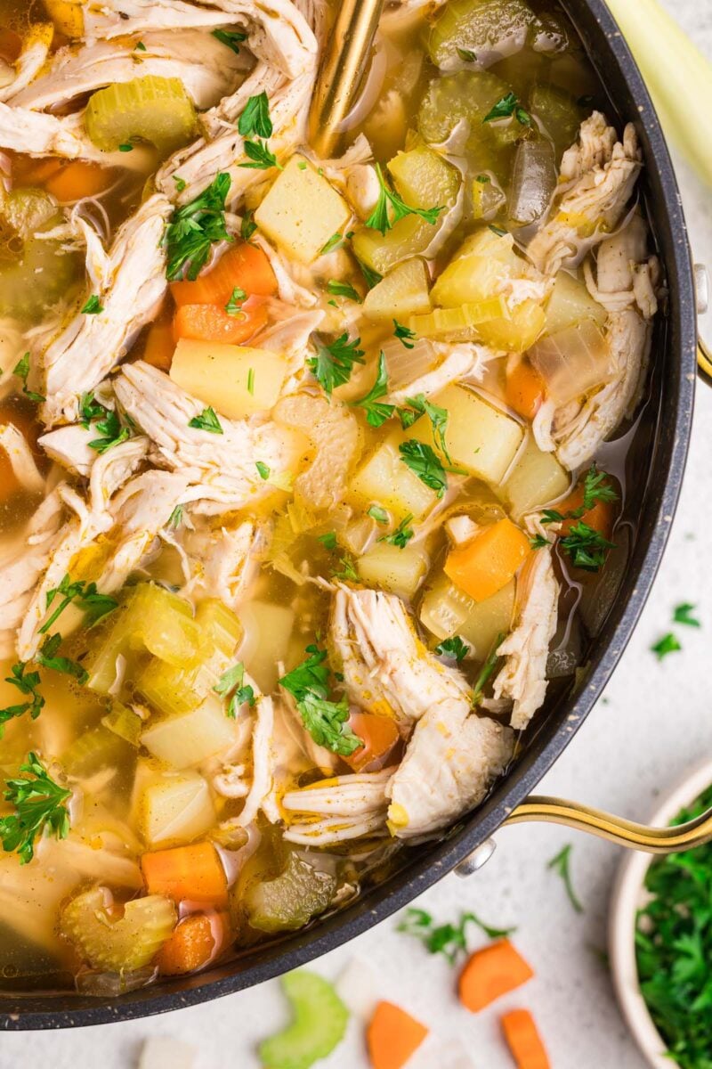 Chicken Potato Soup in a dutch oven with more ingredients on the side.