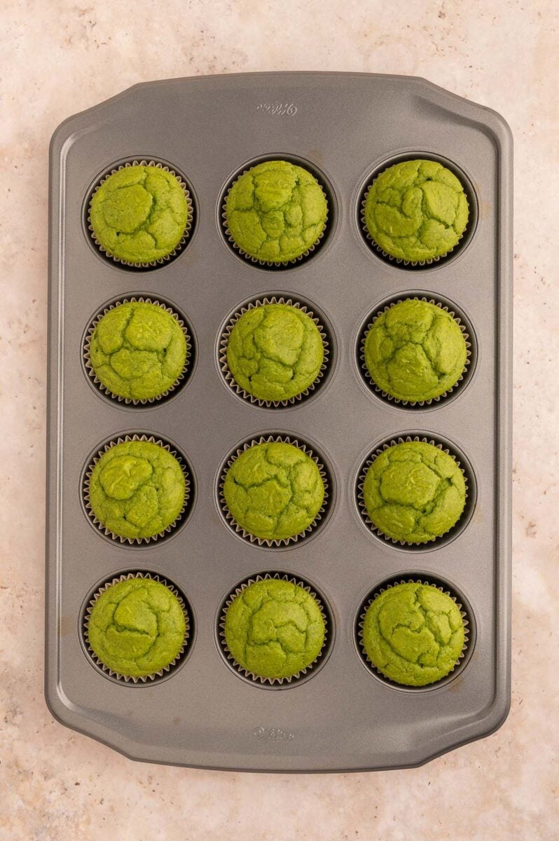 Green spinach muffins in a muffin tin fresh out of the oven.