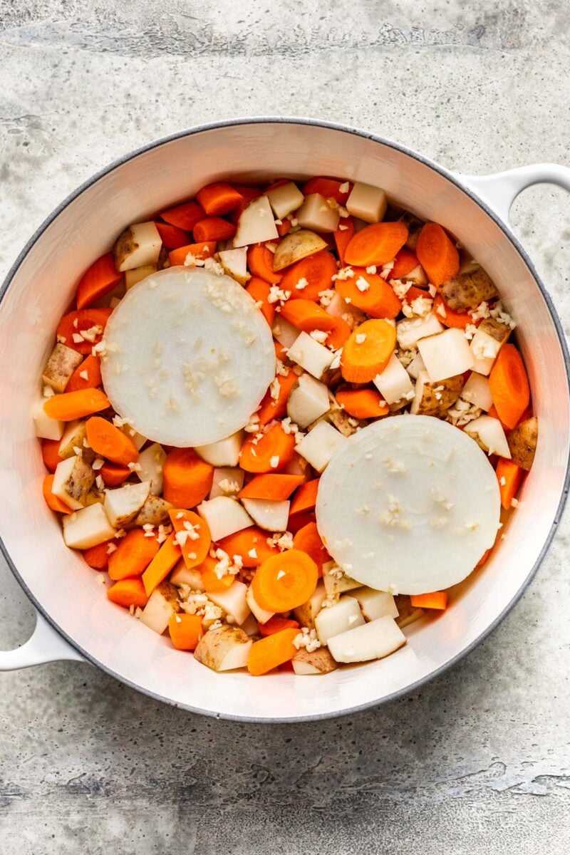 Carrots, potatoes, a sliced onion, and minced garlic in a large dutch oven.
