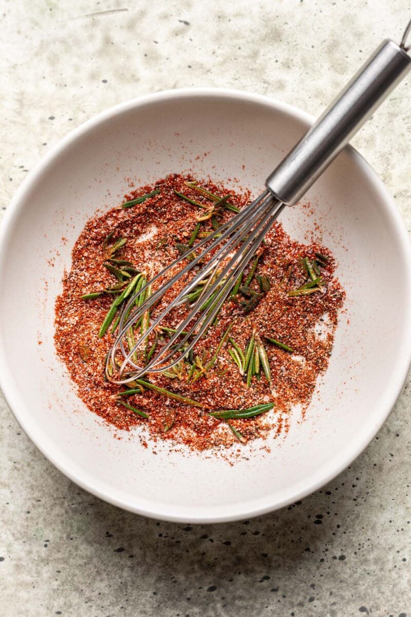Seasoning for dutch oven whole chicken in a small bowl with a whisk stirring together.
