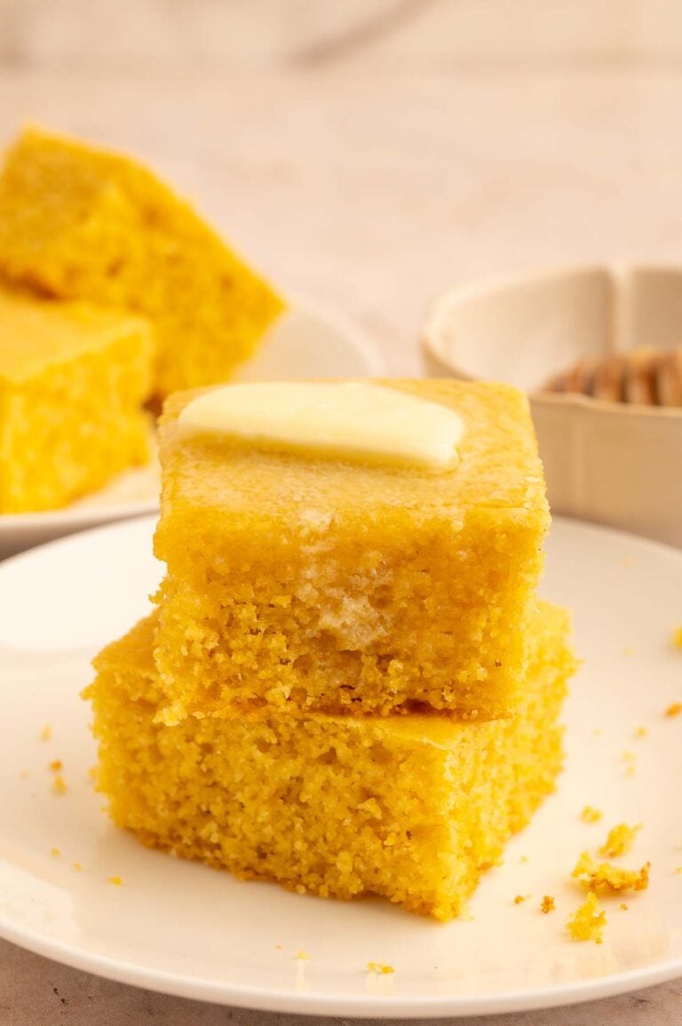 Two pieces of cornbread stacked on each other with a pat of butter on top.