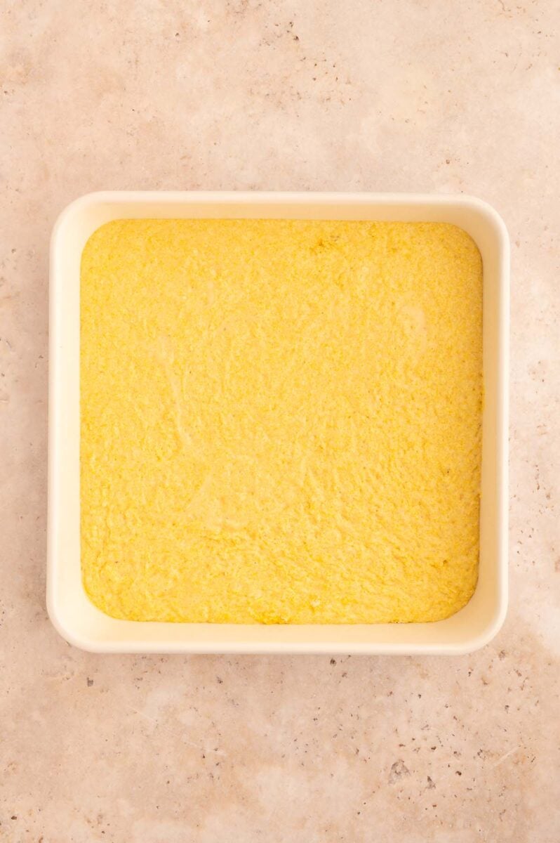 Unbaked healthy cornbread in a square baking pan on a counter. 