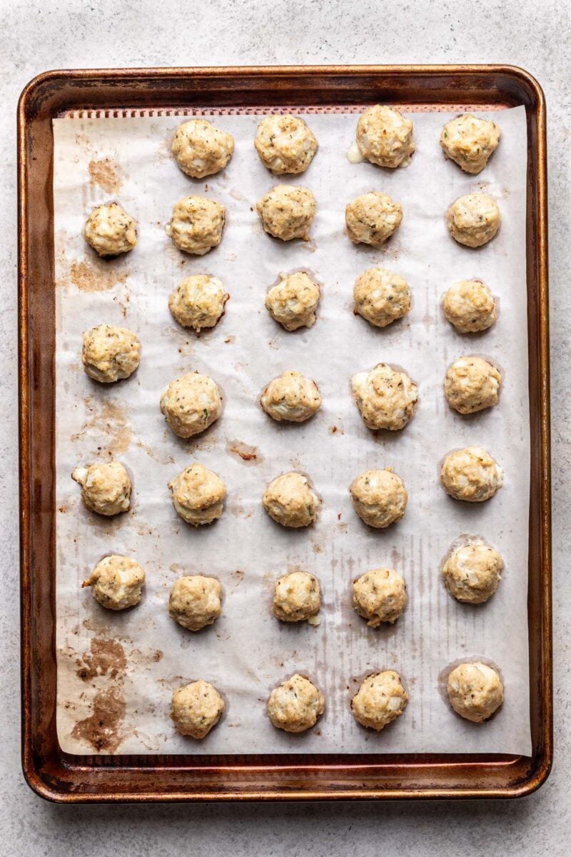 Mini Chicken Meatballs on a parchment lined baking sheet. 