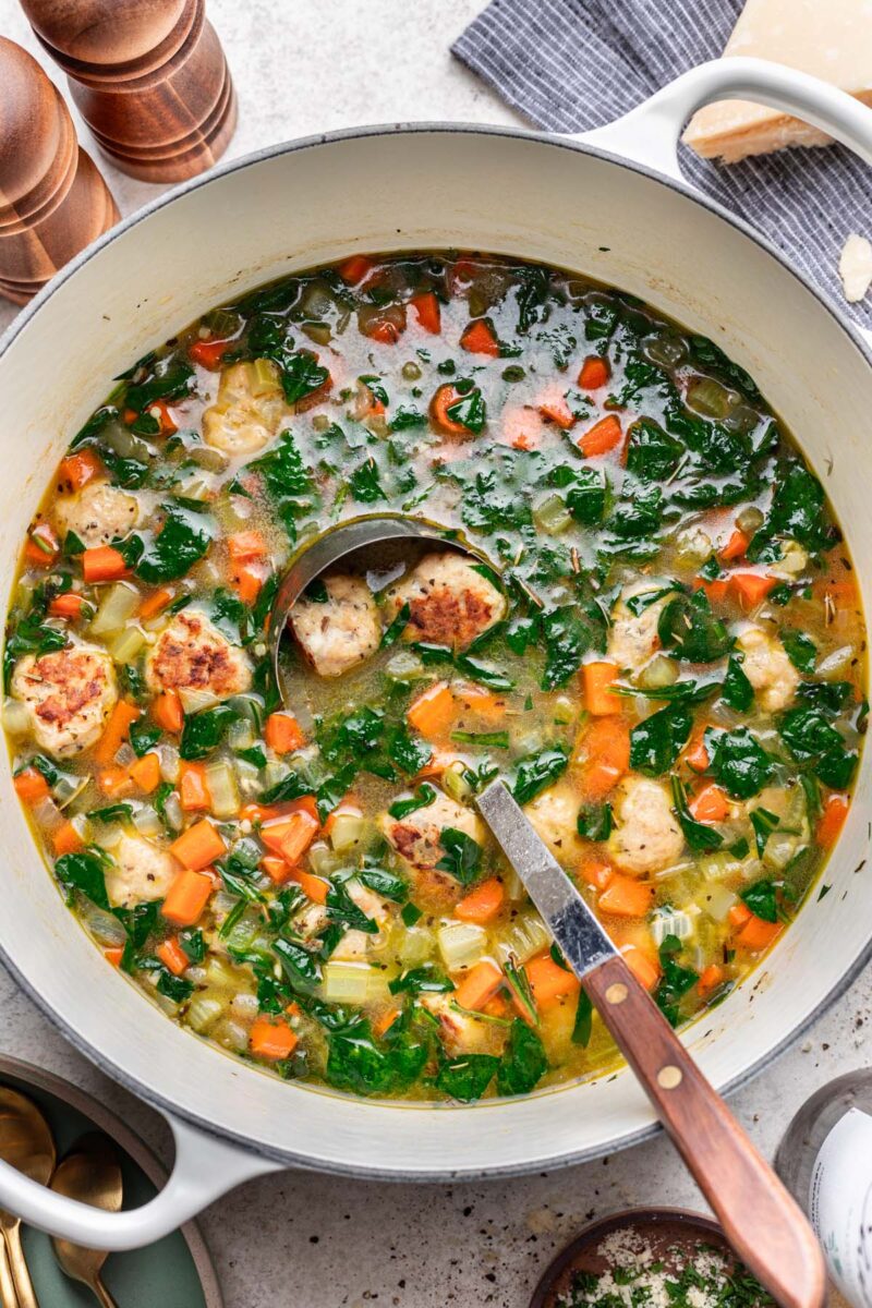 Chicken meatball Soup in a large dutch oven with a ladle dipped in it. 